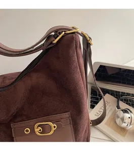 Détail d'un sac à bandoulière en daim marron avec boucle en bronze et lanière en cuir