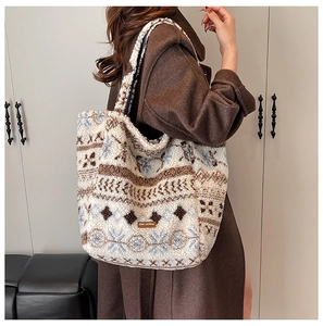 Close-up of large plush tote bag featuring snowflake patterns and a leather label