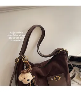 Détail de la bandoulière réglable et de l'ourson sur un sac fourre-tout en daim brun