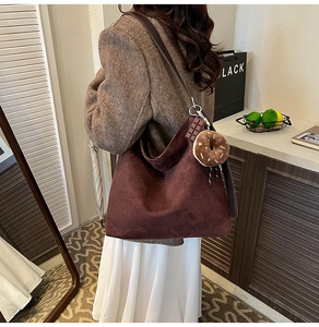 Close-up of a brown suede hobo bag featuring a playful donut-shaped plush charm