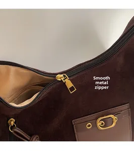 Détail de la fermeture éclair dorée et des ferrures sur le sac en daim marron foncé