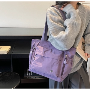 Détail du sac cabas en nylon violet avec poche zippée et compartiments latéraux à cordon