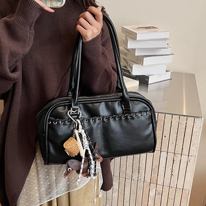 Detalle de bolso Boston en piel sintética negra con ojales y dijes de teckel
