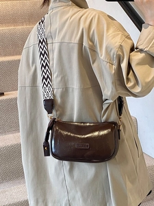 Deep brown glossy pillow bag with geometric wide strap for casual crossbody style