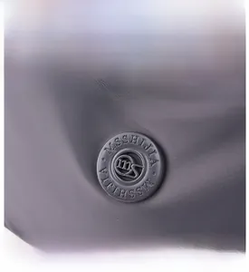 Detail of waterproof nylon fabric and round brand logo on a purple crossbody bag