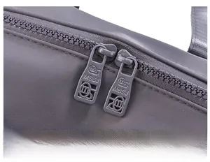 Detail of high-quality smooth dual zippers on a waterproof grey crossbody handbag