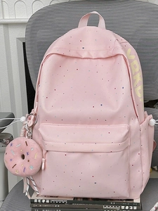 Pink student backpack with colorful polka dots and cute donut pendant on a chair