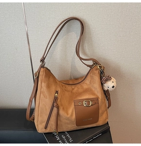 Detail of brown faux suede tote bag with zipper pockets and a cute plush dog charm