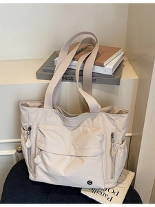 Grand sac fourre-tout minimaliste en nylon beige avec poches fonctionnelles sur canapé