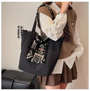 Detailed side view of large canvas tote bag with black and white patterned fleece trim