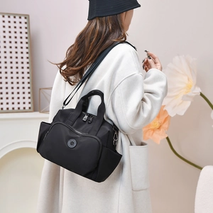 Detail of black waterproof nylon tote bag featuring front zip pocket and brand logo