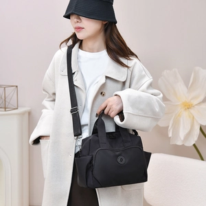 Close-up of a black waterproof nylon handbag with multi-pockets and adjustable strap