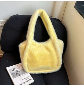 Detail of soft bright yellow plush faux fur tote bag resting on a black chair