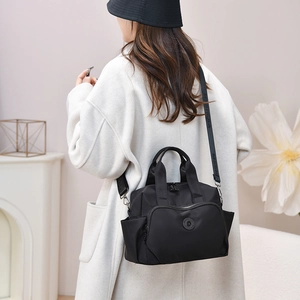 Black waterproof nylon tote bag shown on a model in a stylish indoor setting