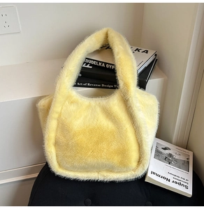 Close-up of bright yellow faux fur tote bag on a dark stool with aesthetic book props