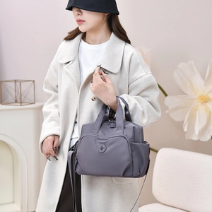 Detail of waterproof nylon tote bag with multiple pockets shown on model in cozy home setting