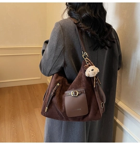 Détail du sac cabas en daim marron foncé avec poche en cuir et breloque ours sur modèle