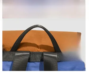 Detail view of durable black webbed handle on an orange and blue backpack top