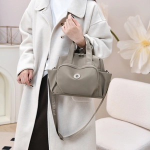 Detail of khaki nylon handbag featuring wide branded shoulder strap and metal logo buckle