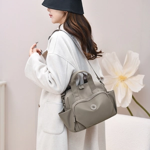 Close-up of waterproof nylon handbag showing multiple zipper pockets and wide strap