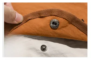 Macro detail of high-quality metal snap button on a dual-tone outdoor nylon backpack