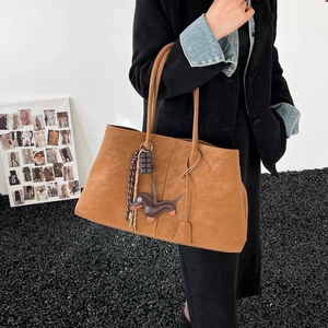 Detail der hellbraunen Leder-Tote-Bag mit Dackel-Anhänger und Schokoladen-Accessoire