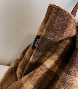 Macro detail of brown plaid textured fabric and premium stitched side label on tote bag
