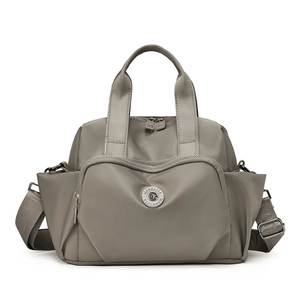 Close-up of waterproof taupe tote bag with metal logo detail and adjustable strap