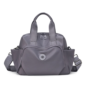 Detail view of grey waterproof nylon handbag with multiple pockets and wide strap