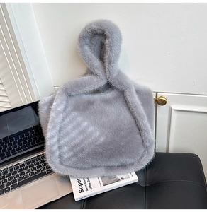 Detail of grey faux fur tote bag with stylish knotted handle on a modern office desk