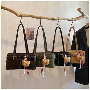 Detail of trendy underarm bags in four colors hanging on a branch with bear charms