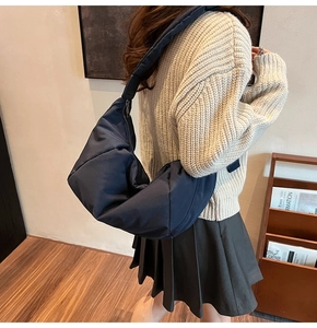 Détail du sac croissant en nylon bleu marine avec bandoulière large dans un intérieur
