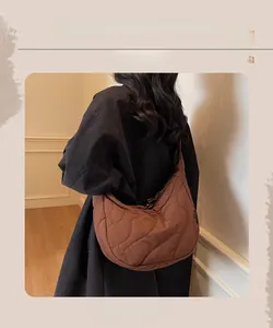 Gros plan d'un sac bandoulière marron foncé matelassé avec texture bouffante ondulée