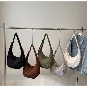 Quilted crescent crossbody bags in five colors hanging on a metal rack for display