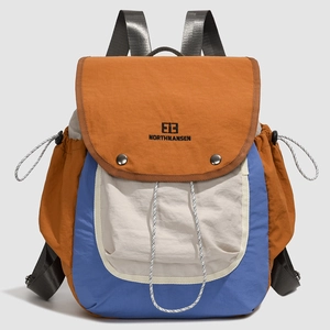 Detail of multi-color nylon backpack featuring drawstring side pockets and embroidery