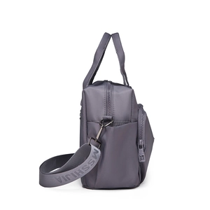 Detail view of mauve nylon handbag with wide adjustable shoulder strap and side pocket