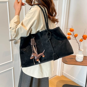 Große schwarze Vintage-Wildleder-Tragetasche mit Anhängern, präsentiert von einem Model