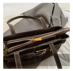 Detail show of dark brown leather tote bag with white stitching and gold hardware