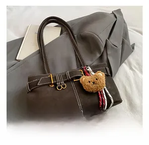 Detail of retro brown underarm bag with contrast white stitching and bear charm