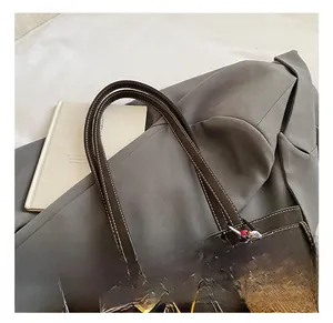 Detail of brown leather tote bag with white stitching and a cute plush bear charm