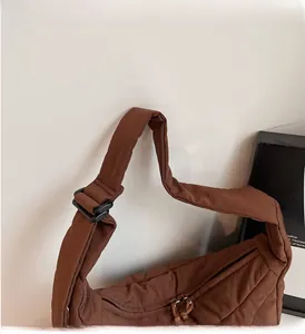 Detail of brown quilted bag showing reinforced shoulder strap and adjustable plastic buckle