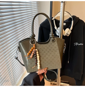 Détail du sac seau vert foncé avec motif à carreaux et glands en perles colorées