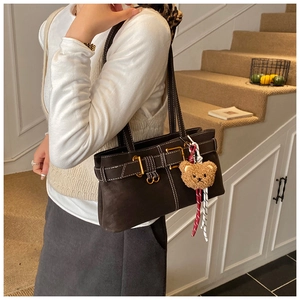 Detail of dark brown tote bag with white contrast stitching and plush bear charm