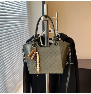 Détail du sac seau vert olive à motif damier avec perles en bois et finitions argentées