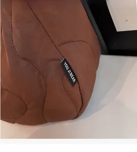 Close-up of brown quilted shoulder bag with wave stitching and branded brand label