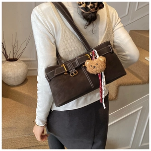 Detail of dark brown matte underarm bag with contrast stitching and teddy bear charm