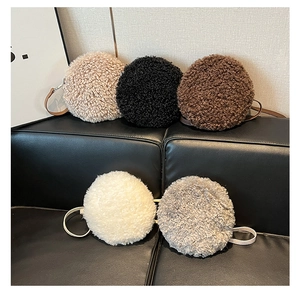 Detailed close-up showing five colors of plush lambskin round bags on a black texture bench