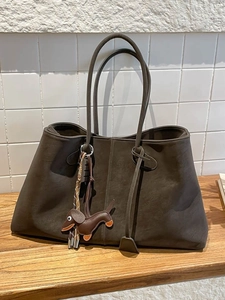 Vintage dunkelbraune Shopper Tasche mit Dackel Anhänger auf einem Holzregal