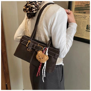 Detail of dark brown retro shoulder bag with white contrast stitching and bear charm