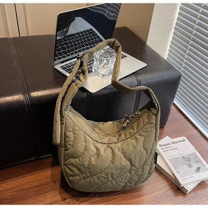Détail de la texture matelassée sur un sac bandoulière vert dans un décor lifestyle